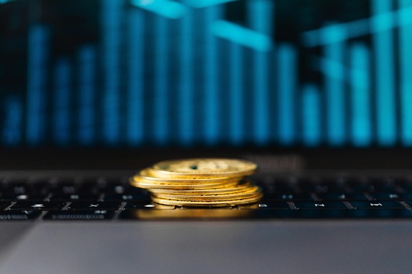 Cryptocurrency coins resting on a laptop keyboard with a price chart on screen