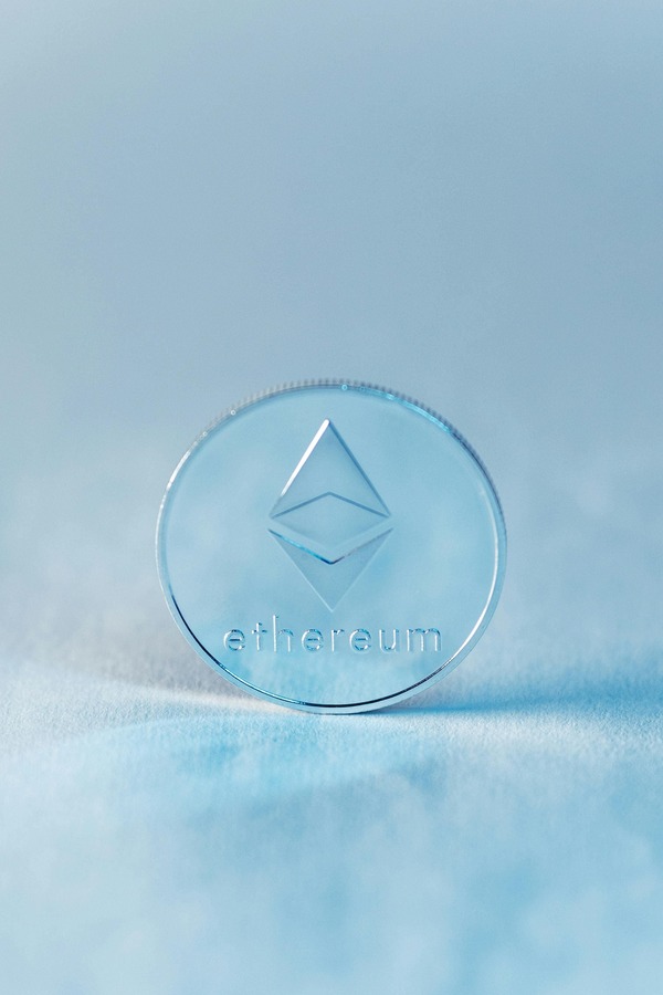Translucent Ethereum-style cryptocurrency coin on a light blue background