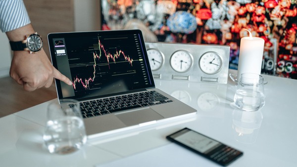 Row of world clocks next to a laptop displaying a cryptocurrency price chart